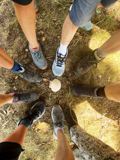 Füße in Wanderschuhen mit Jakobsmuschel