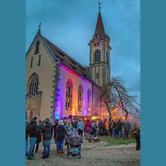 Die Schönberger Kirche in der Dämmerung mit Personen auf dem Glockenmarkt